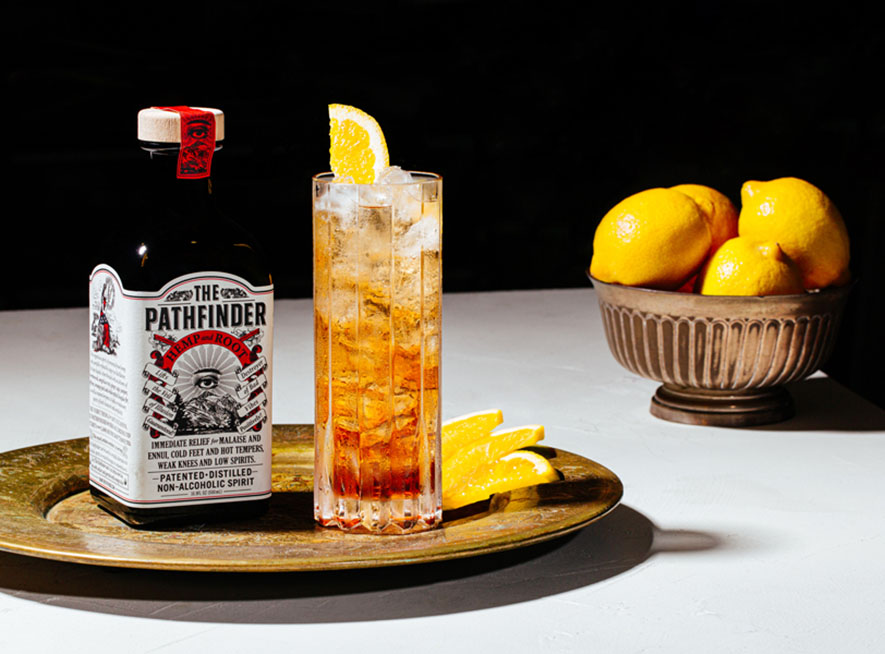 Signature cocktail, the Pathfinder Spritz, in a collins glass with orange slices nearby